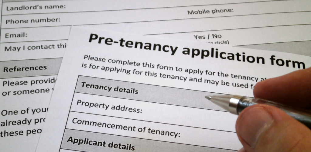 Property Management Close-up of a hand filling out a pre-tenancy application form, a key step in securing rental assistance or housing approval