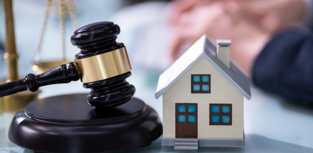 Gavel beside a miniature house symbolizing legal proceedings related to real estate value, property rights, or foreclosure in a courtroom setting