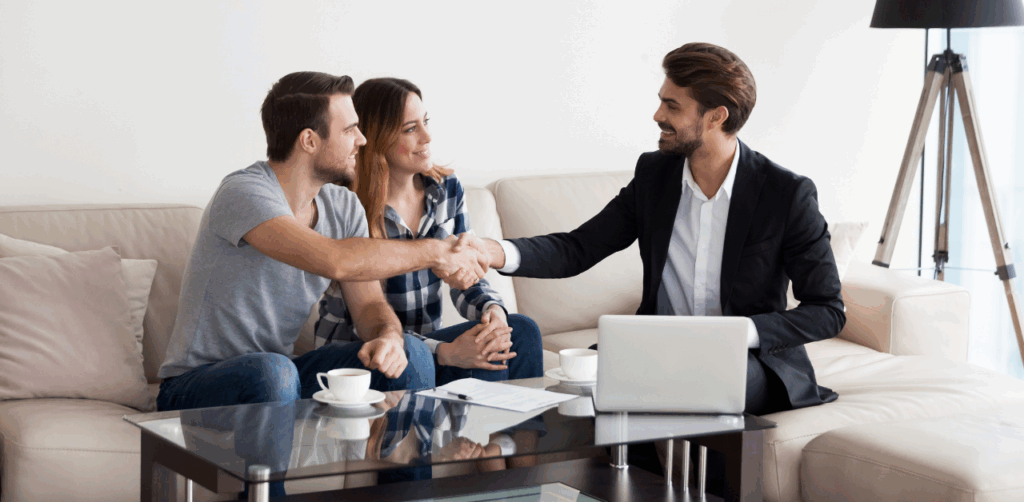 Couple shakes hands with a real estate agent in a bright living room during a property meeting