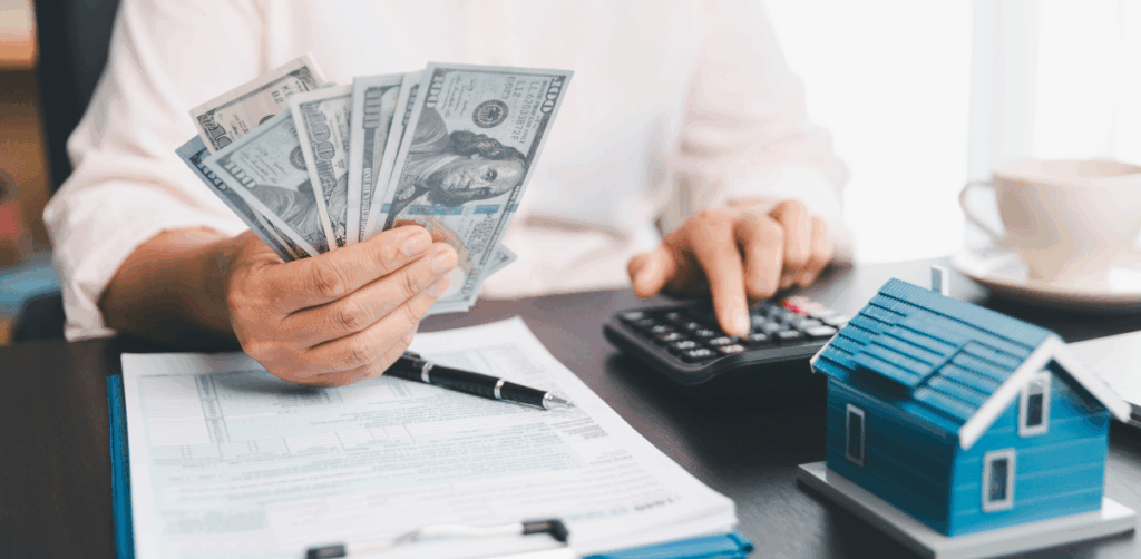 Person counting cash with calculator and home loan documents nearby