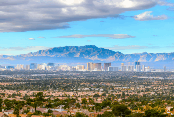 Wide view of Las Vegas skyline with mountains in the background and residential homes in the foreground