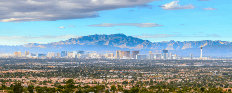 Wide view of Las Vegas skyline with mountains in the background and residential homes in the foreground