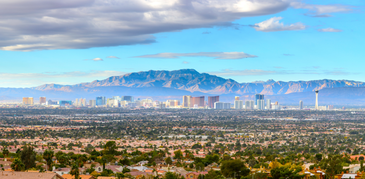 Wide view of Las Vegas skyline with mountains in the background and residential homes in the foreground