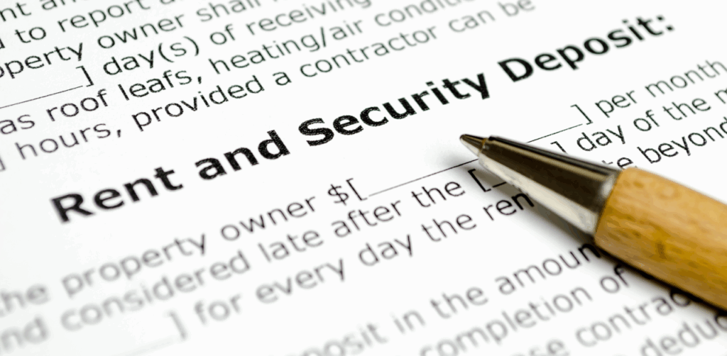 Property Management Close-up of a rent and security deposit lease agreement with a wooden pen resting on the paper