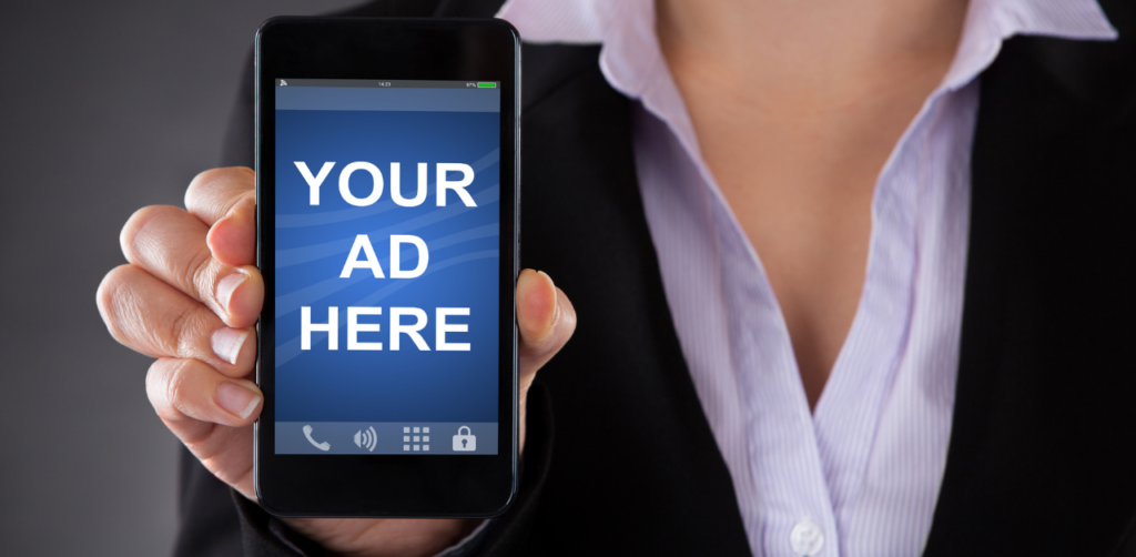 A person in business attire holding a smartphone displaying the text Your Ad Here on the screen