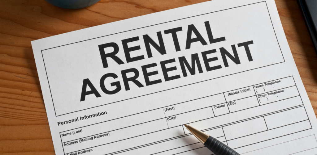 A rental agreement form placed on a wooden surface with a pen lying on top, ready for signing