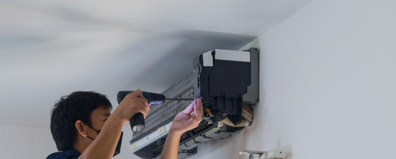 Technician repairs a wall-mounted air conditioner using a power drill