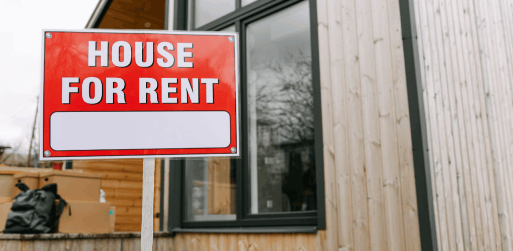 Red and white “House for Rent” sign displayed in front of a modern home