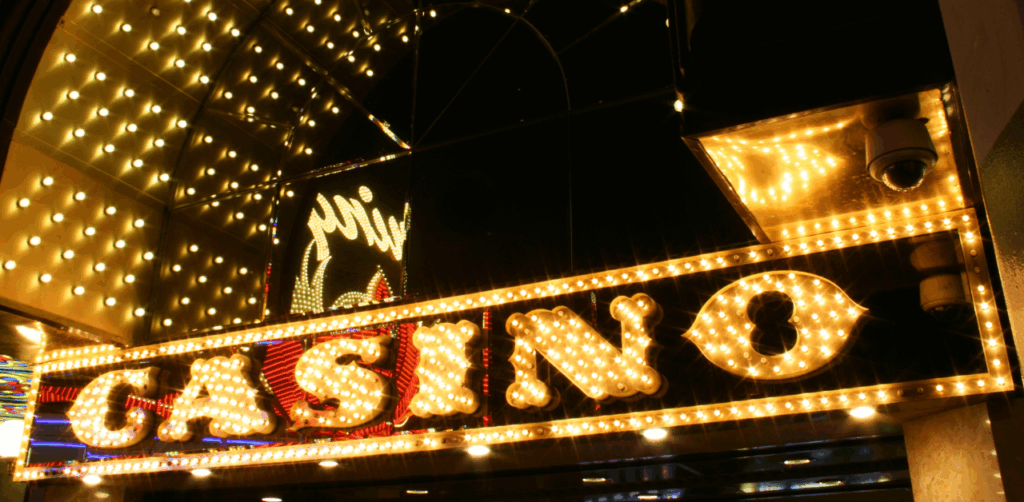 Brightly lit casino entrance sign glowing with yellow and white marquee lights at night