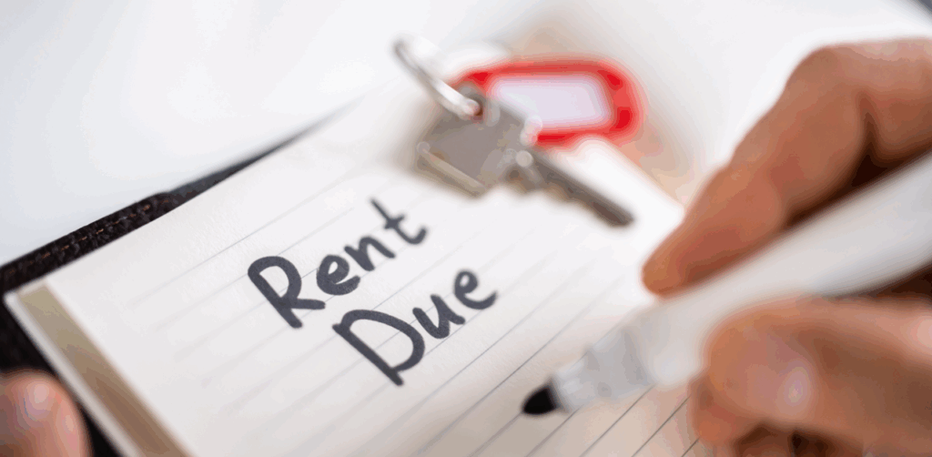 Close-up of “Rent Due” written in a notebook beside house keys, highlighting rental payment reminder