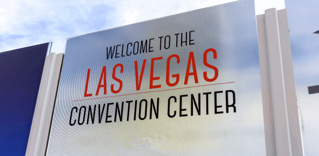 Close-up of a sign reading “Welcome to the Las Vegas Convention Center,” with bold red and black text under a blue sky