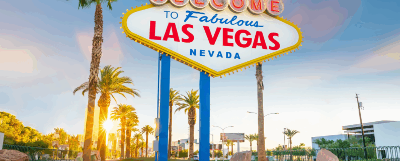 Famous “Welcome to Fabulous Las Vegas, Nevada” sign stands tall at sunset, surrounded by palm trees and a warm golden glow