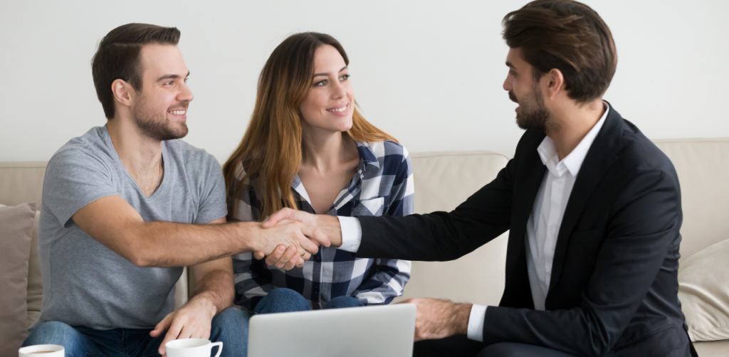 A couple shaking hands with a suited professional, suggesting a positive meeting or agreement