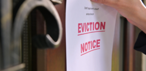 Close-up of an Eviction Notice being placed on a door, printed in bold red letters