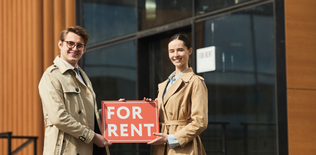 Real Estate Agents Holding 'For Rent' Sign