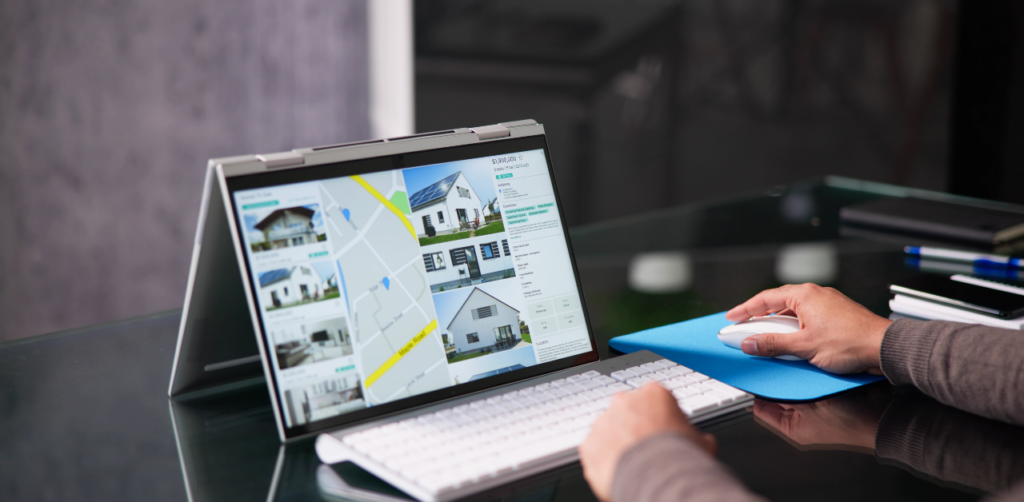 Person browsing home listings on a touchscreen laptop with map and pricing details, representing digital tools used in modern property management for evaluating and marketing real estate