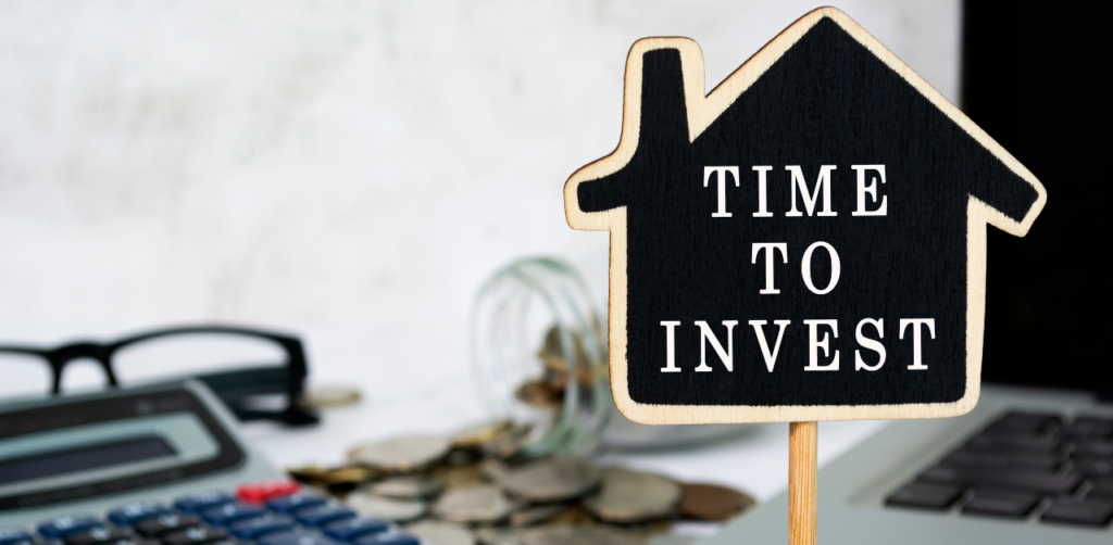 Property Management Time to Invest sign shaped like a house with coins, a calculator, and glasses in the background