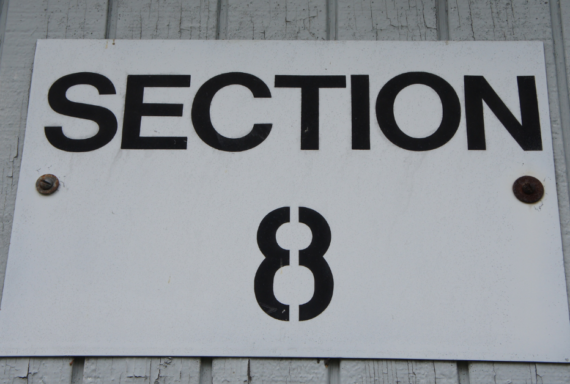 White sign labeled 'Section 8' mounted on a wall, referencing a federal housing assistance program for low-income renters