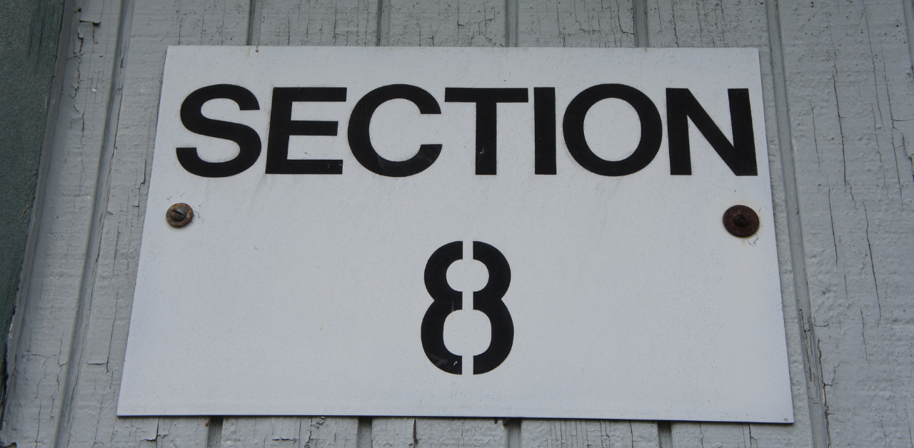 White sign labeled 'Section 8' mounted on a wall, referencing a federal housing assistance program for low-income renters
