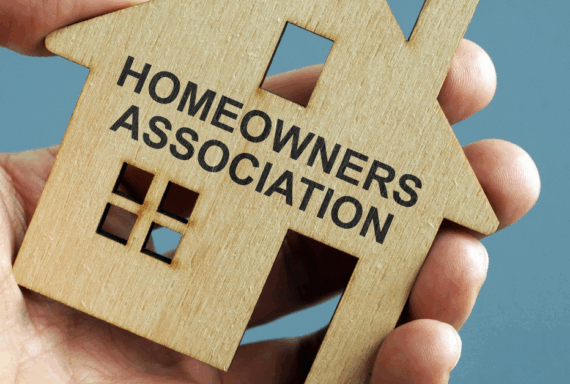 Wooden house cutout labeled Homeowners Association held in a person's hand