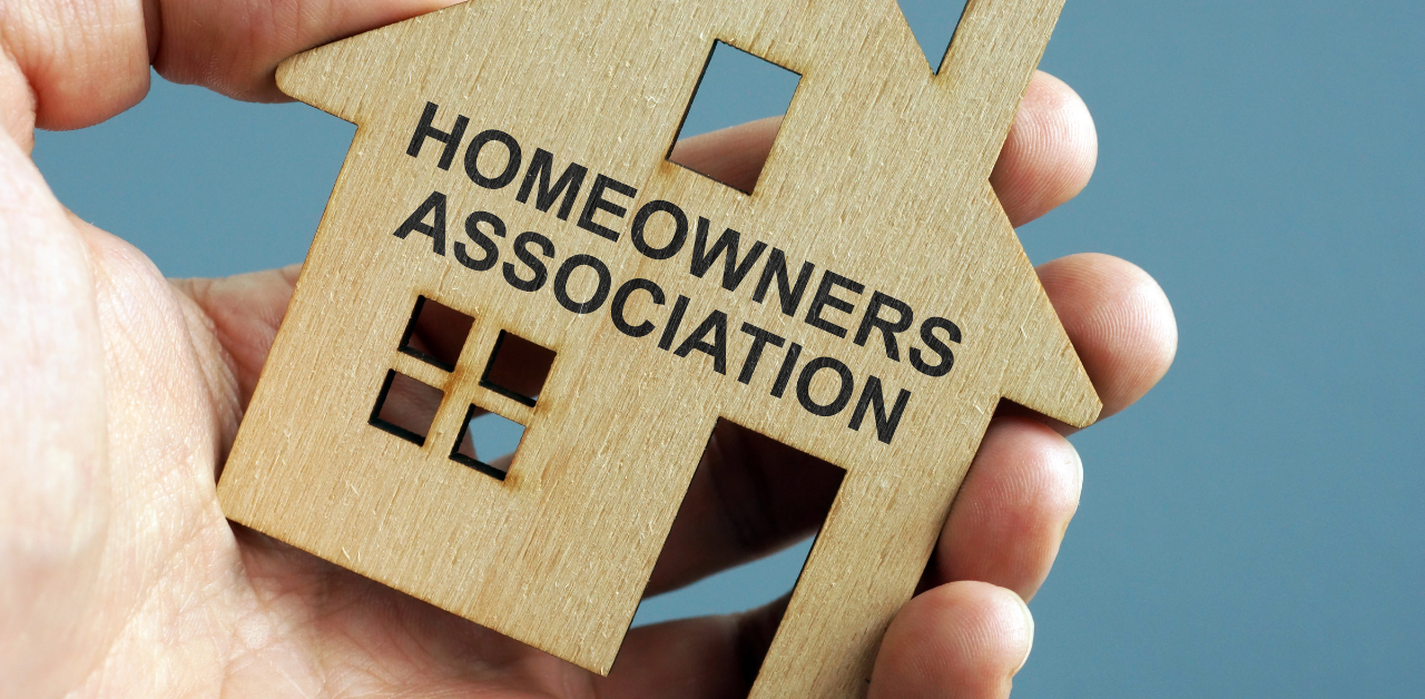 Wooden house cutout labeled Homeowners Association held in a person's hand