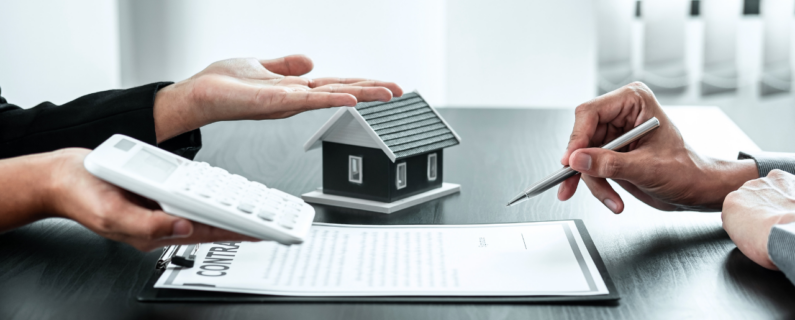 Hands discussing a real estate contract with calculator and house model, highlighting home buying costs and agreement