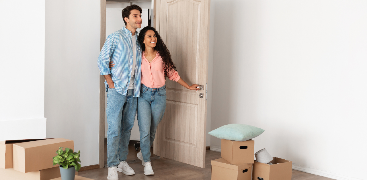 Happy couple entering new home with boxes, symbolizing moving in, homeownership, and new beginnings