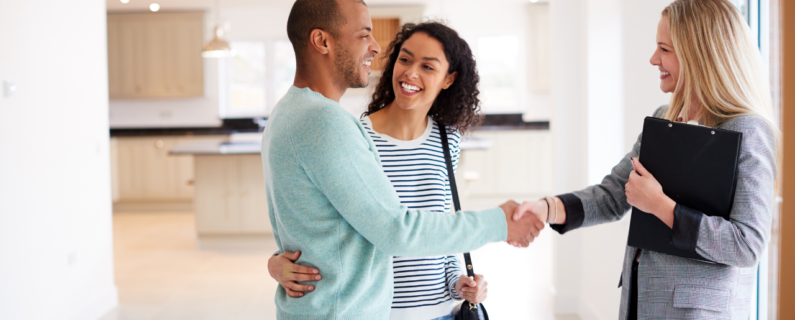 Happy couple shaking hands with real estate agent in new home, symbolizing property deal, home purchase, and agreement