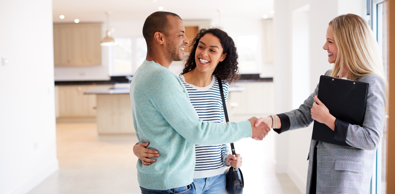 Happy couple shaking hands with real estate agent in new home, symbolizing property deal, home purchase, and agreement