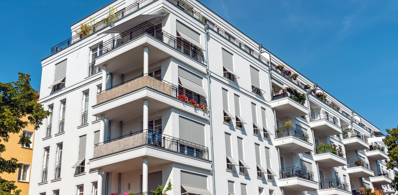 Modern apartment building with multiple balconies and large windows, showcasing urban residential real estate and contemporary housing design under a clear blue sky