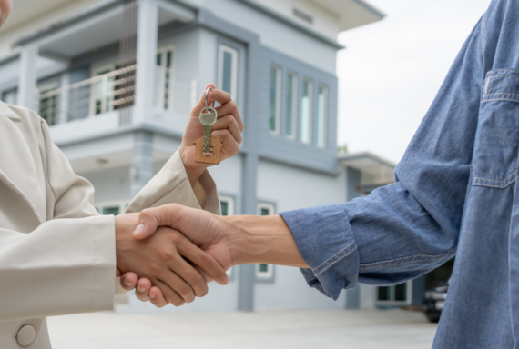 Real estate agent handing over house keys during handshake, symbolizing home purchase, property sale, and ownership transfer