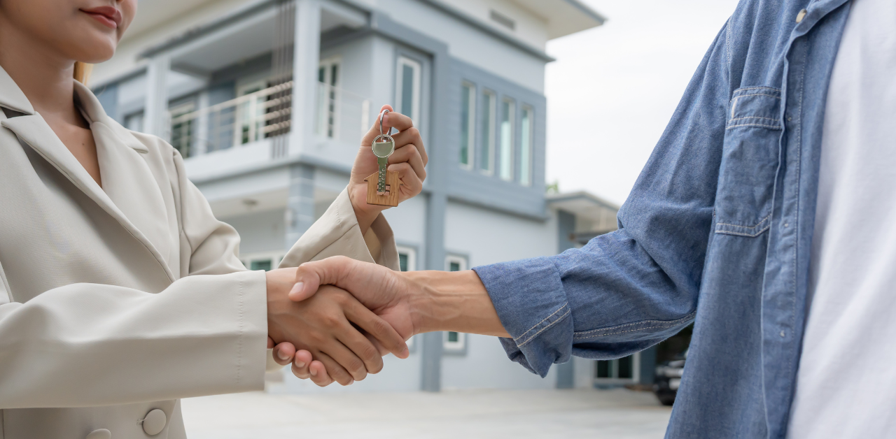 Real estate agent handing over house keys during handshake, symbolizing home purchase, property sale, and ownership transfer