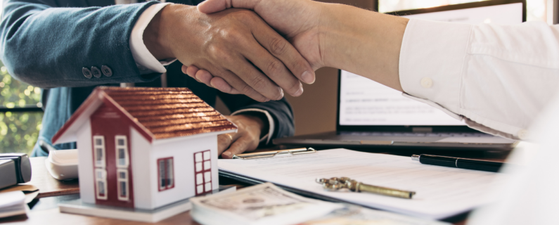 Real estate deal sealed with handshake over house model, keys, and cash, symbolizing property sale and financial agreement