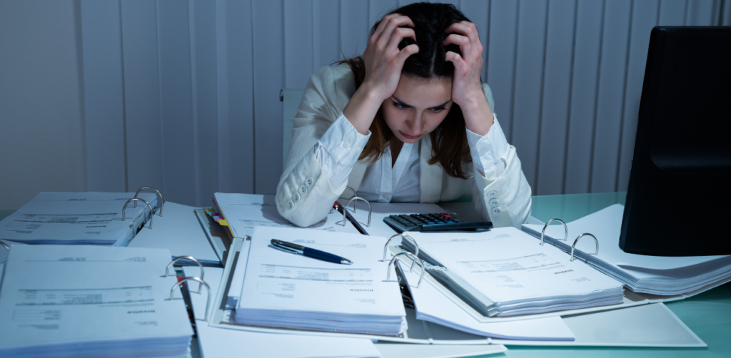 Stressed woman reviewing bills and paperwork with calculator, representing financial stress, debt management, and budgeting challenges