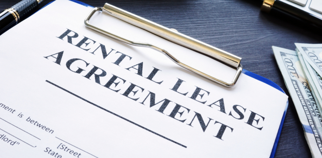 Close-up of a rental lease agreement on a clipboard with a pen and cash nearby, representing property leasing, rent payments, and real estate contracts