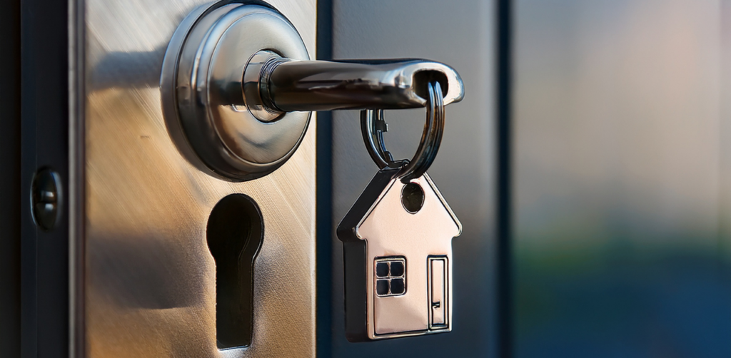Close-up of key in door lock with house-shaped keychain, symbolizing home ownership, security, and property access