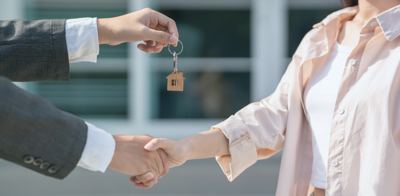 Real estate agent hands over house keys while shaking hands with a new homeowner